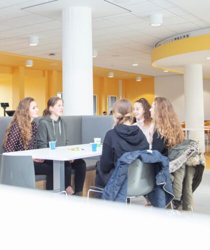 3 scholieren in gesprek met 2 studenten van de opleiding Bouwkunde in het restaurant van HZ Groene Woud