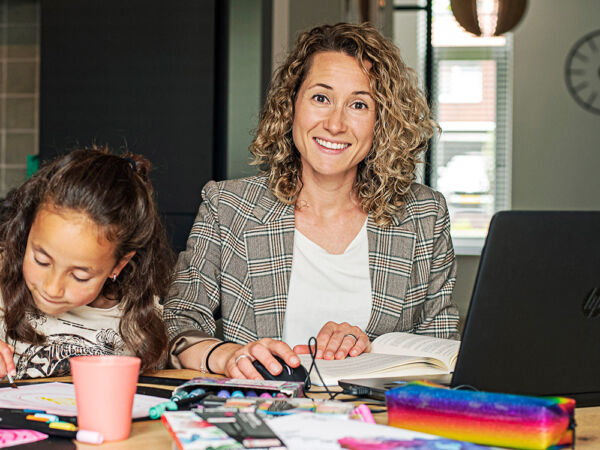 Deeltijd student Tamara maakt haar huiswerk aan de eettafel met knutselende kinderen